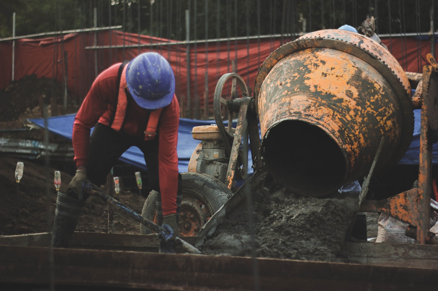 Worker in a hard hat setting pipe in an open utility trench